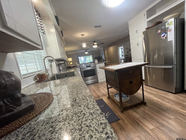 kitchen with white cabinetry, sink, stainless steel appliances, light stone countertops, and light wood-type flooring