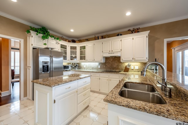 kitchen featuring a center island, sink, stainless steel fridge, black electric stovetop, and white cabinets