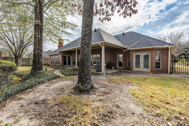 back of property featuring french doors, a patio area, and a lawn