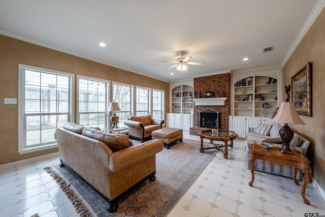 living room with built in features, a brick fireplace, ceiling fan, and crown molding