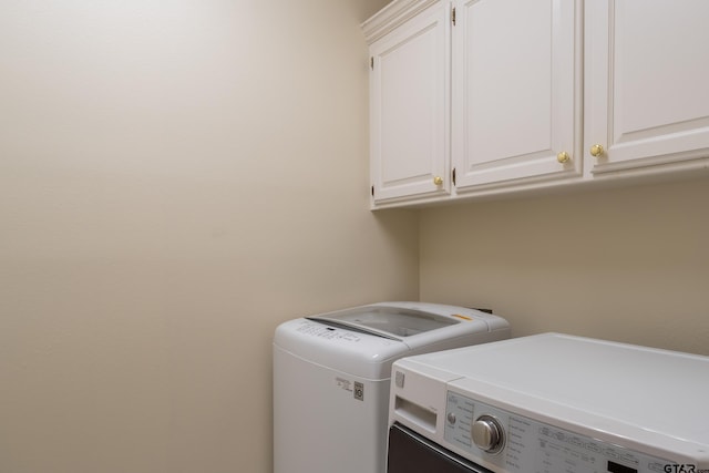 clothes washing area with washer and clothes dryer and cabinets