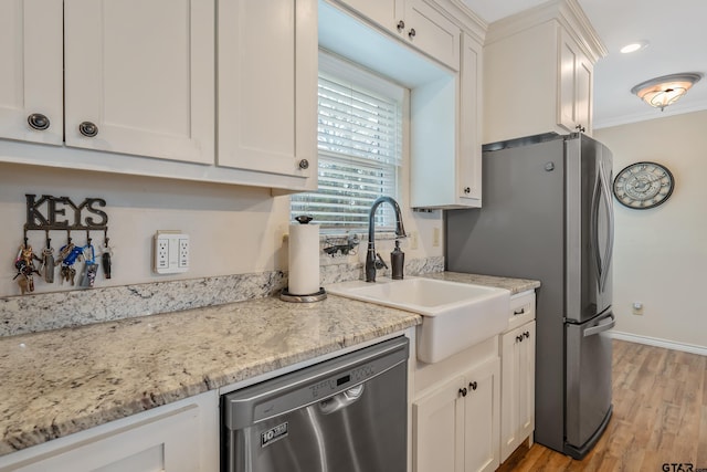 kitchen with ornamental molding, stainless steel appliances, sink, light hardwood / wood-style flooring, and white cabinets