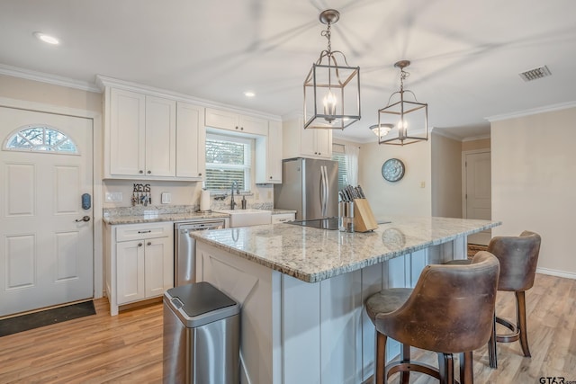 kitchen with white cabinetry, pendant lighting, stainless steel appliances, and light hardwood / wood-style floors