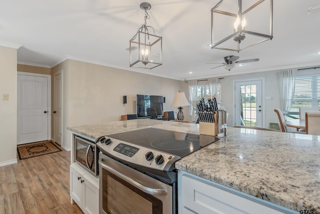 kitchen with pendant lighting, white cabinets, ceiling fan with notable chandelier, appliances with stainless steel finishes, and light hardwood / wood-style floors