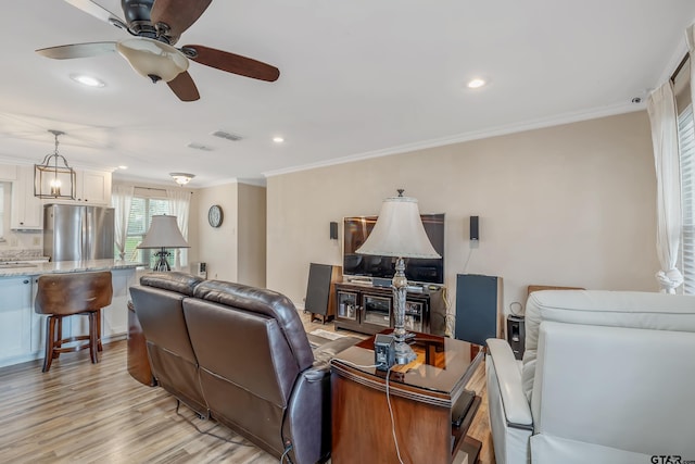 living room featuring crown molding, ceiling fan, and light wood-type flooring