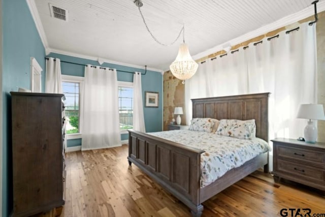 bedroom with light hardwood / wood-style floors, crown molding, and an inviting chandelier