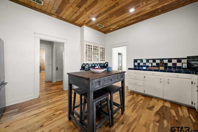 kitchen featuring white cabinets, light wood-type flooring, wood ceiling, and tile countertops