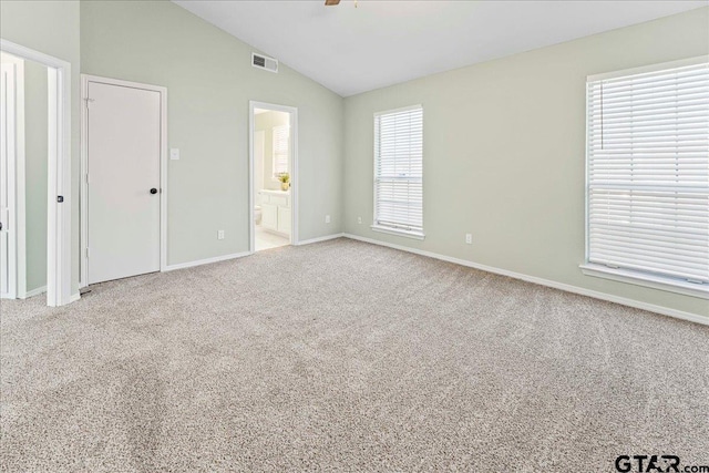 unfurnished bedroom with ceiling fan, ensuite bathroom, carpet flooring, and vaulted ceiling