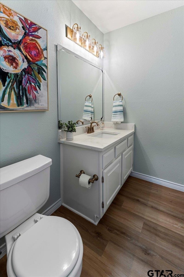 bathroom with wood-type flooring, toilet, and vanity