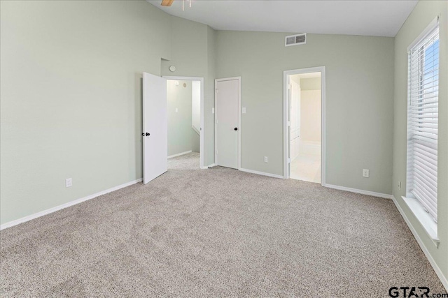 unfurnished bedroom with ensuite bath, vaulted ceiling, and light carpet