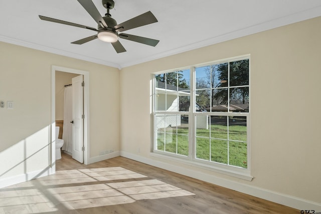 empty room featuring a wealth of natural light, crown molding, ceiling fan, and light hardwood / wood-style floors