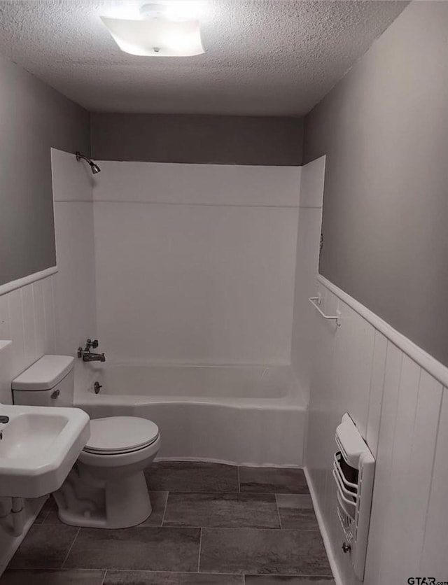 7094 Eleanor St, Tyler, TX 75708 - bathroom with a textured ceiling, wainscoting, toilet, and shower / bathtub combination