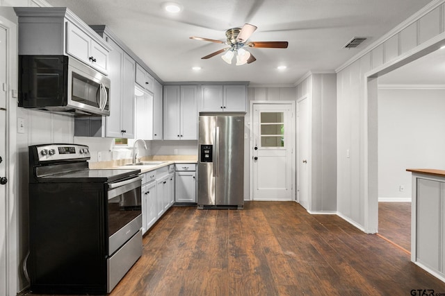 2811 Rollingwood Dr, Tyler, TX 75701 - kitchen with stainless steel appliances, a sink, a ceiling fan, crown molding, and dark wood finished floors