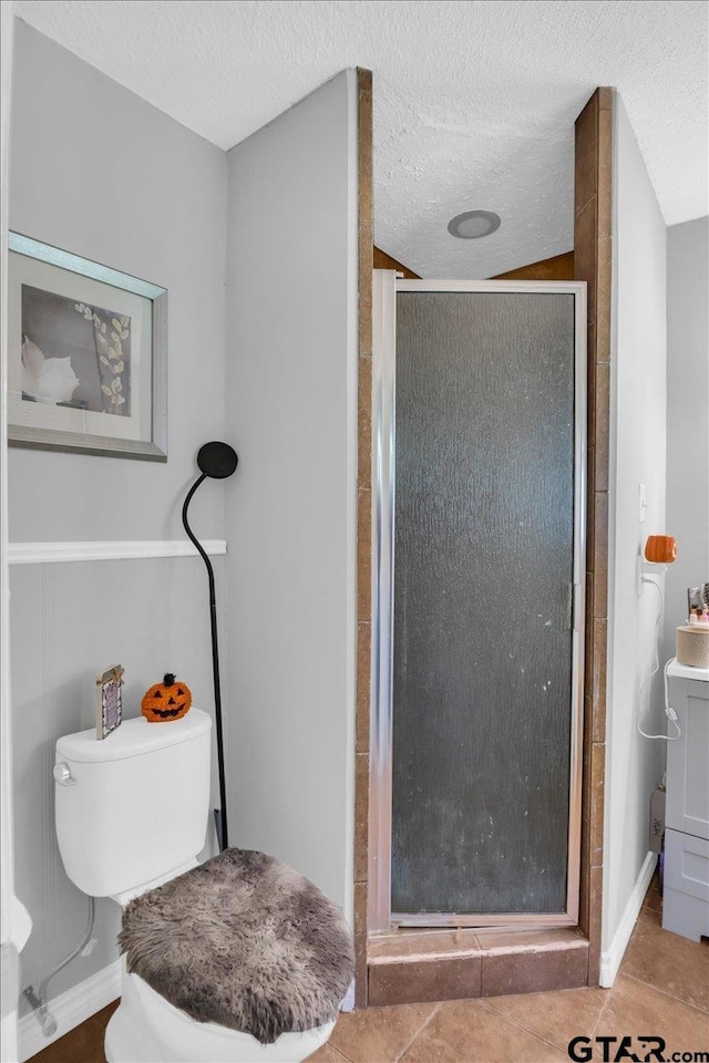 bathroom featuring toilet, tile patterned flooring, a textured ceiling, and walk in shower