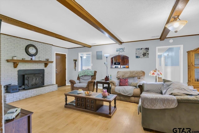 living room with a textured ceiling, beam ceiling, a fireplace, and light hardwood / wood-style flooring