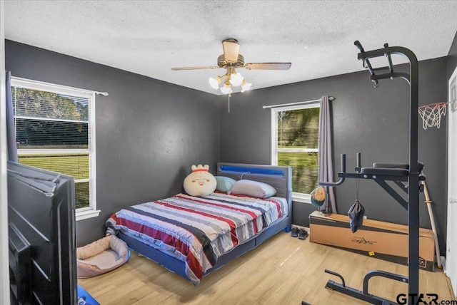 bedroom with ceiling fan, hardwood / wood-style floors, and a textured ceiling