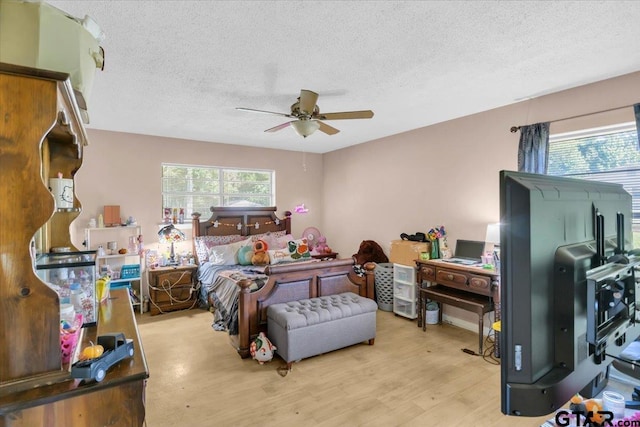 bedroom featuring multiple windows, light wood-type flooring, a textured ceiling, and ceiling fan