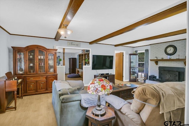 living room with beamed ceiling, light hardwood / wood-style floors, and a brick fireplace