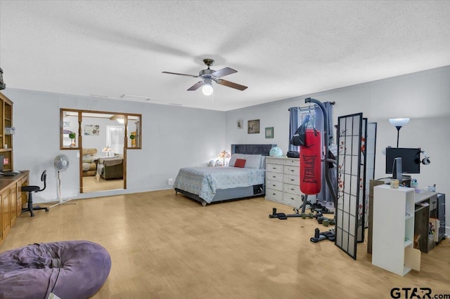 bedroom with ceiling fan, a textured ceiling, and light wood-type flooring