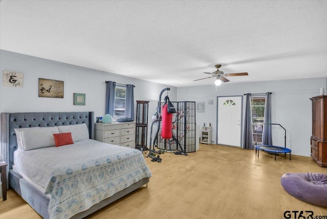 bedroom featuring light wood-type flooring, a textured ceiling, and ceiling fan