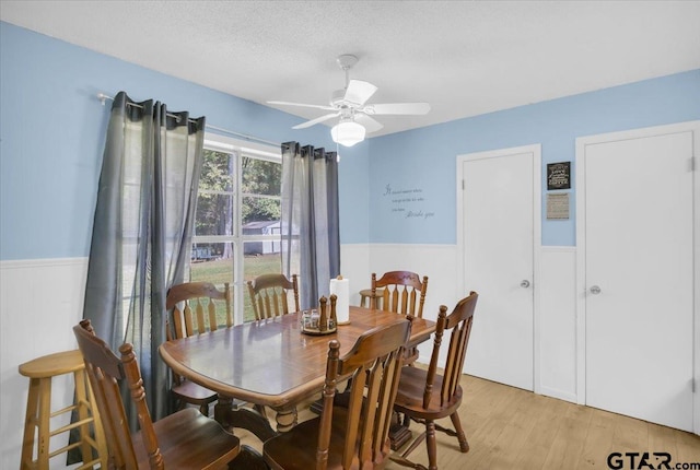 dining area with ceiling fan, light hardwood / wood-style floors, and a textured ceiling