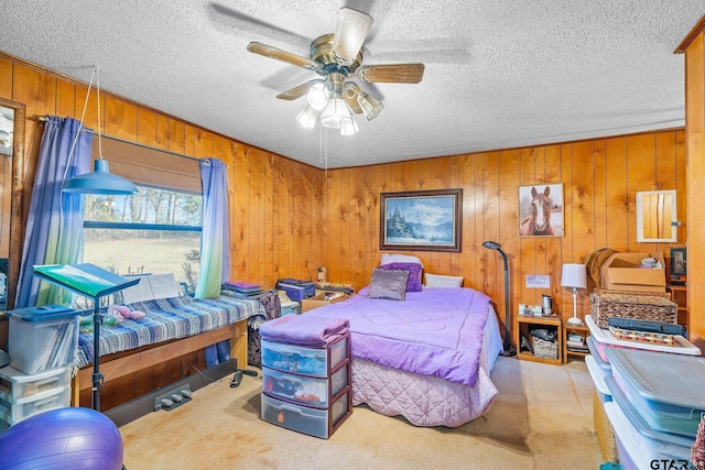 bedroom featuring ceiling fan, light colored carpet, a textured ceiling, and wooden walls