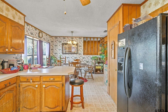 kitchen featuring kitchen peninsula, black refrigerator with ice dispenser, a textured ceiling, decorative light fixtures, and a breakfast bar area