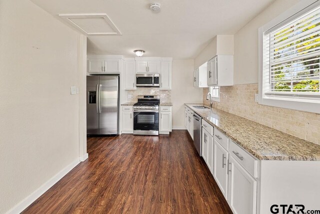 kitchen featuring appliances with stainless steel finishes, light stone counters, dark hardwood / wood-style floors, and white cabinets