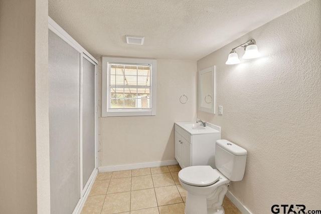 bathroom featuring vanity, tile patterned flooring, a textured ceiling, and toilet