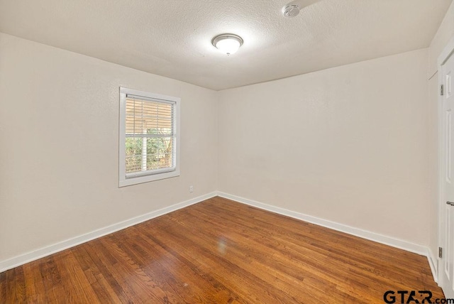 empty room featuring wood-type flooring and a textured ceiling