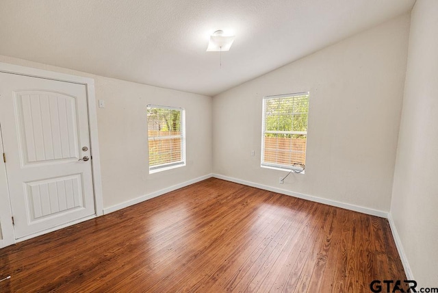 unfurnished room featuring hardwood / wood-style flooring, lofted ceiling, and a healthy amount of sunlight