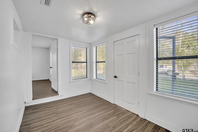 1005 N Rodeo St, Gladewater, TX 75647 - entrance foyer featuring baseboards, a textured ceiling, and wood finished floors