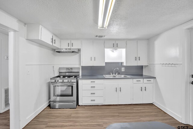 1005 N Rodeo St, Gladewater, TX 75647 - kitchen with gas range, a sink, a textured ceiling, under cabinet range hood, and light wood-type flooring