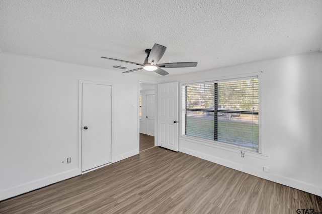1005 N Rodeo St, Gladewater, TX 75647 - unfurnished bedroom featuring a textured ceiling, wood finished floors, baseboards, and ceiling fan