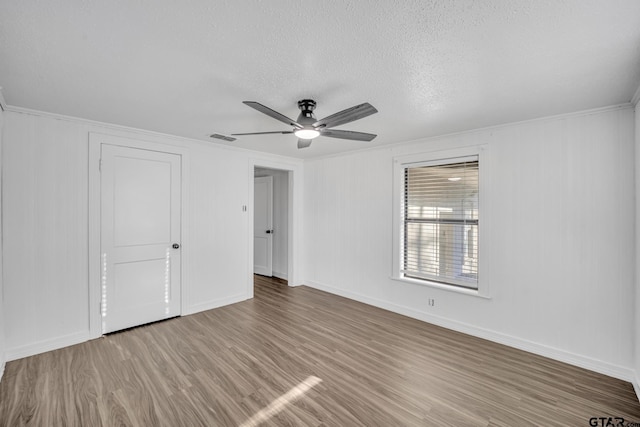 1005 N Rodeo St, Gladewater, TX 75647 - unfurnished bedroom with wood finished floors, a textured ceiling, ornamental molding, baseboards, and a ceiling fan