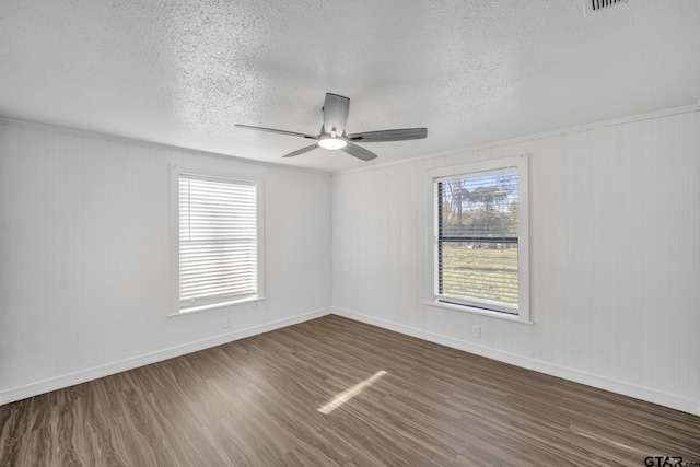 1005 N Rodeo St, Gladewater, TX 75647 - spare room featuring a textured ceiling, dark wood-style flooring, a ceiling fan, and baseboards