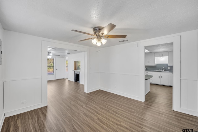 1005 N Rodeo St, Gladewater, TX 75647 - unfurnished room featuring ceiling fan, a textured ceiling, wood finished floors, and a sink