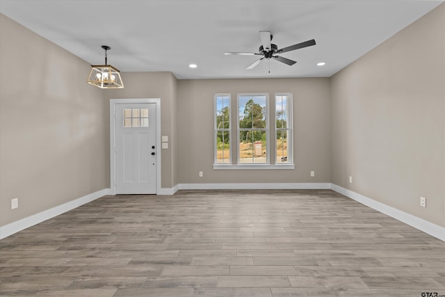 foyer entrance with ceiling fan with notable chandelier and light hardwood / wood-style flooring