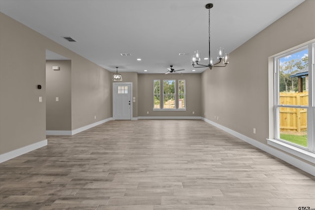 interior space with ceiling fan with notable chandelier and light hardwood / wood-style flooring