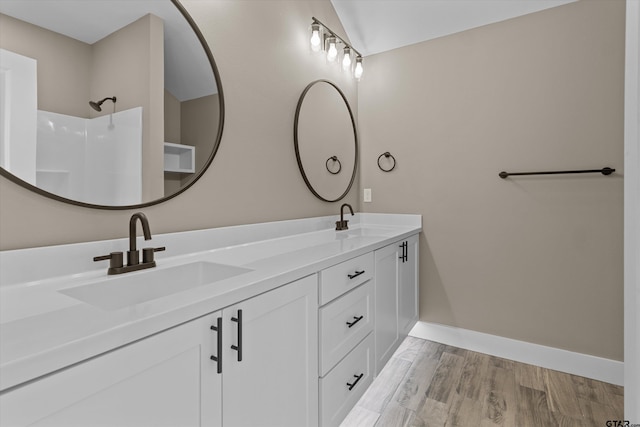 bathroom featuring a shower, wood-type flooring, vanity, and vaulted ceiling