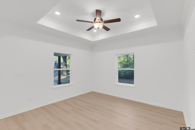 unfurnished room with ceiling fan, light hardwood / wood-style floors, ornamental molding, and a tray ceiling