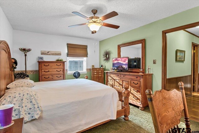 5626 Meadowdale Rd, Flint, TX 75762 - carpeted bedroom with a textured ceiling, a ceiling fan, and a wainscoted wall