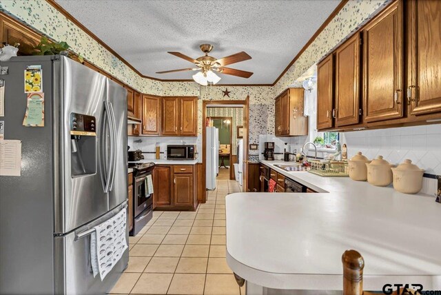 5626 Meadowdale Rd, Flint, TX 75762 - kitchen featuring stainless steel appliances, wallpapered walls, brown cabinetry, light countertops, and ceiling fan