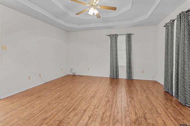 unfurnished bedroom featuring ceiling fan, light hardwood / wood-style floors, and a tray ceiling