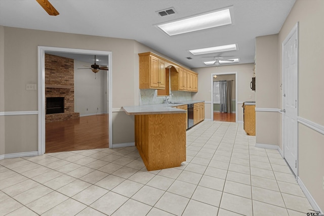 kitchen featuring kitchen peninsula, a fireplace, sink, light tile patterned floors, and dishwasher