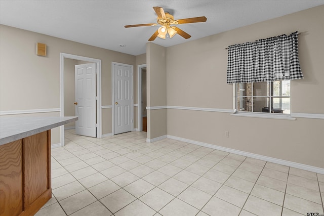 spare room with ceiling fan and light tile patterned floors