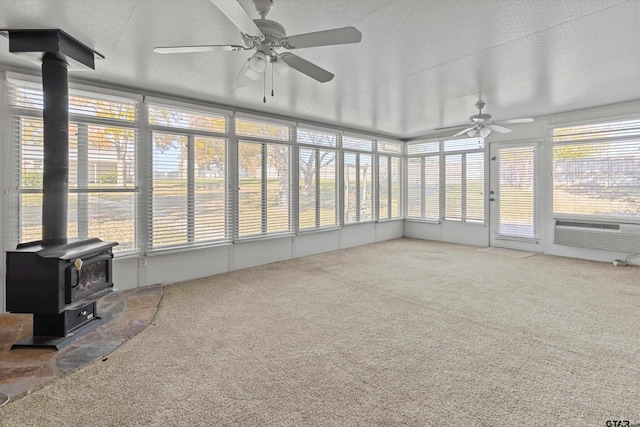 sunroom with plenty of natural light, ceiling fan, a wood stove, and cooling unit