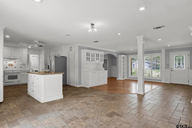 kitchen featuring decorative columns, ceiling fan, a kitchen island, crown molding, and white cabinetry