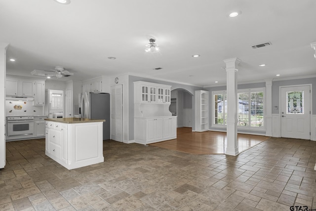 909 Elizabeth St, Gilmer, TX 75644 - kitchen with white electric stove, crown molding, stone tile flooring, under cabinet range hood, and white cabinets