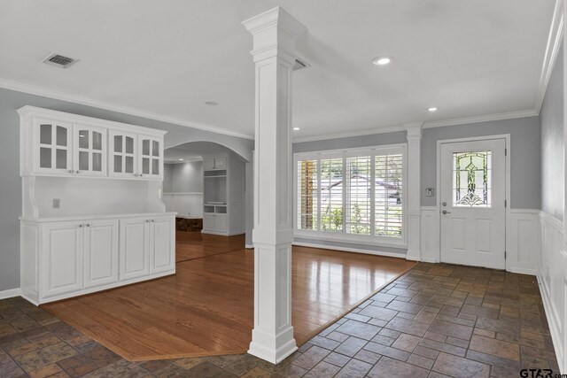909 Elizabeth St, Gilmer, TX 75644 - entrance foyer featuring crown molding, plenty of natural light, wainscoting, decorative columns, and arched walkways